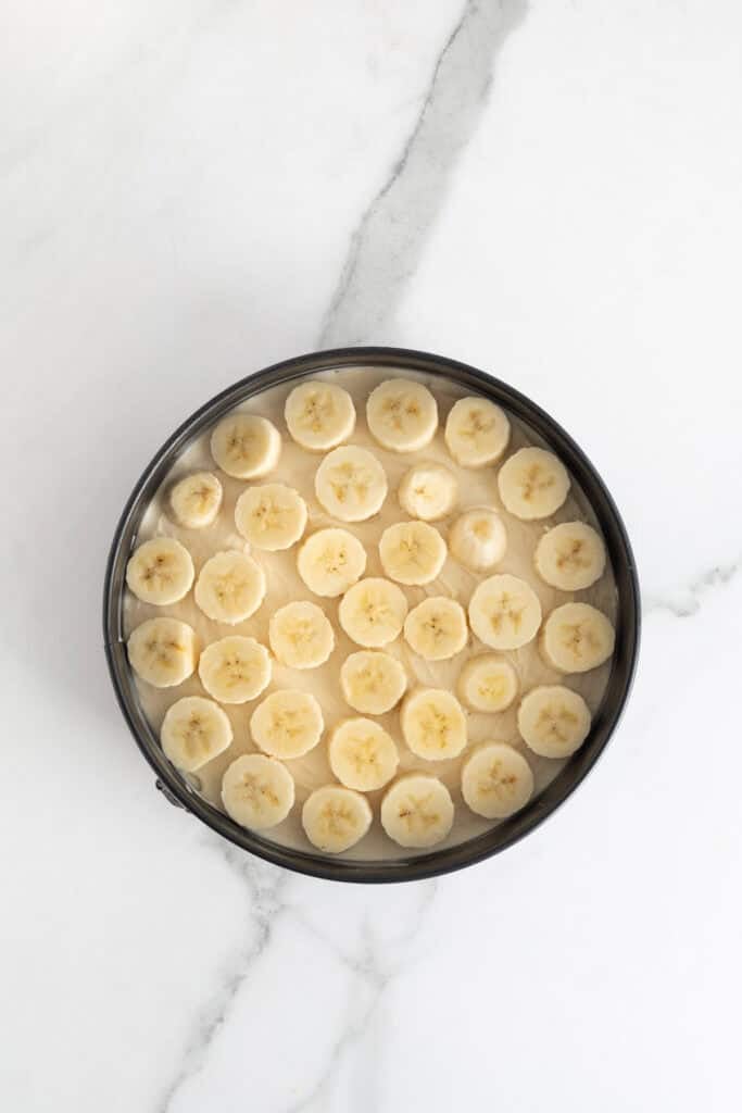 Banana slices added on top of cheesecake filling in springform pan
