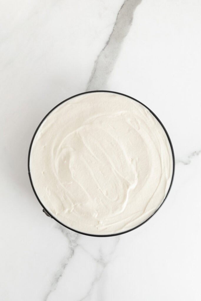 Whipped cream spread on top of a banana cheesecake