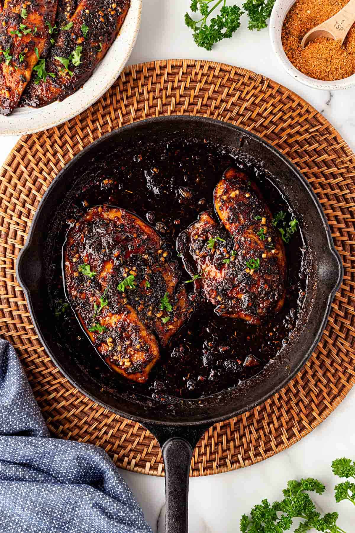 Blackened fish fillets simmering in honey glaze in a cast iron skillet