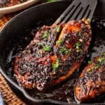 Closeup of blackened fish in a honey sauce inside a cast iron skillet