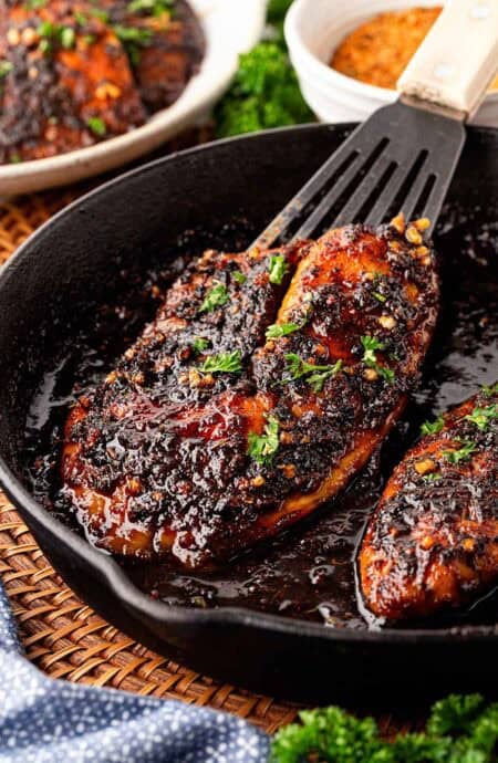 Closeup of blackened fish in a honey sauce inside a cast iron skillet