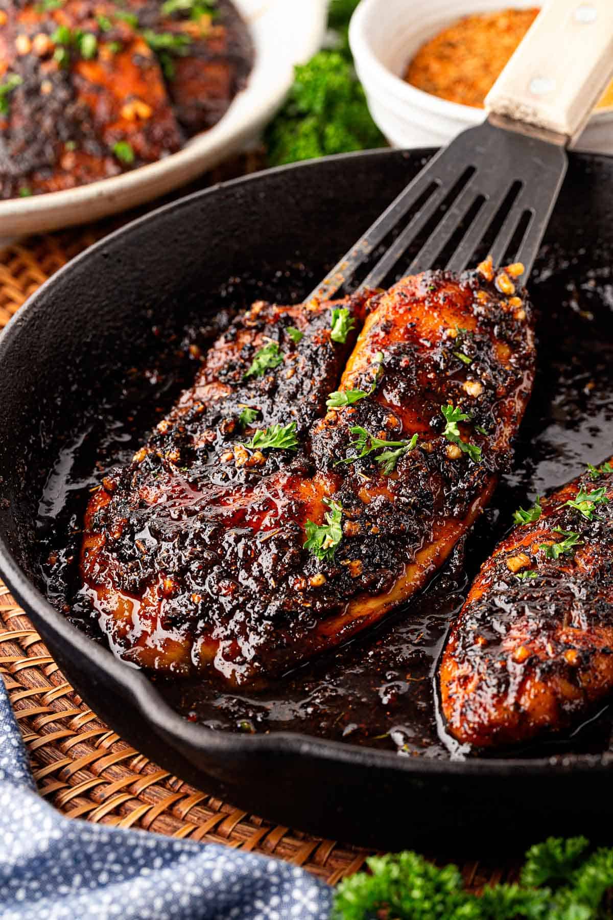 Closeup of blackened fish in a honey sauce inside a cast iron skillet