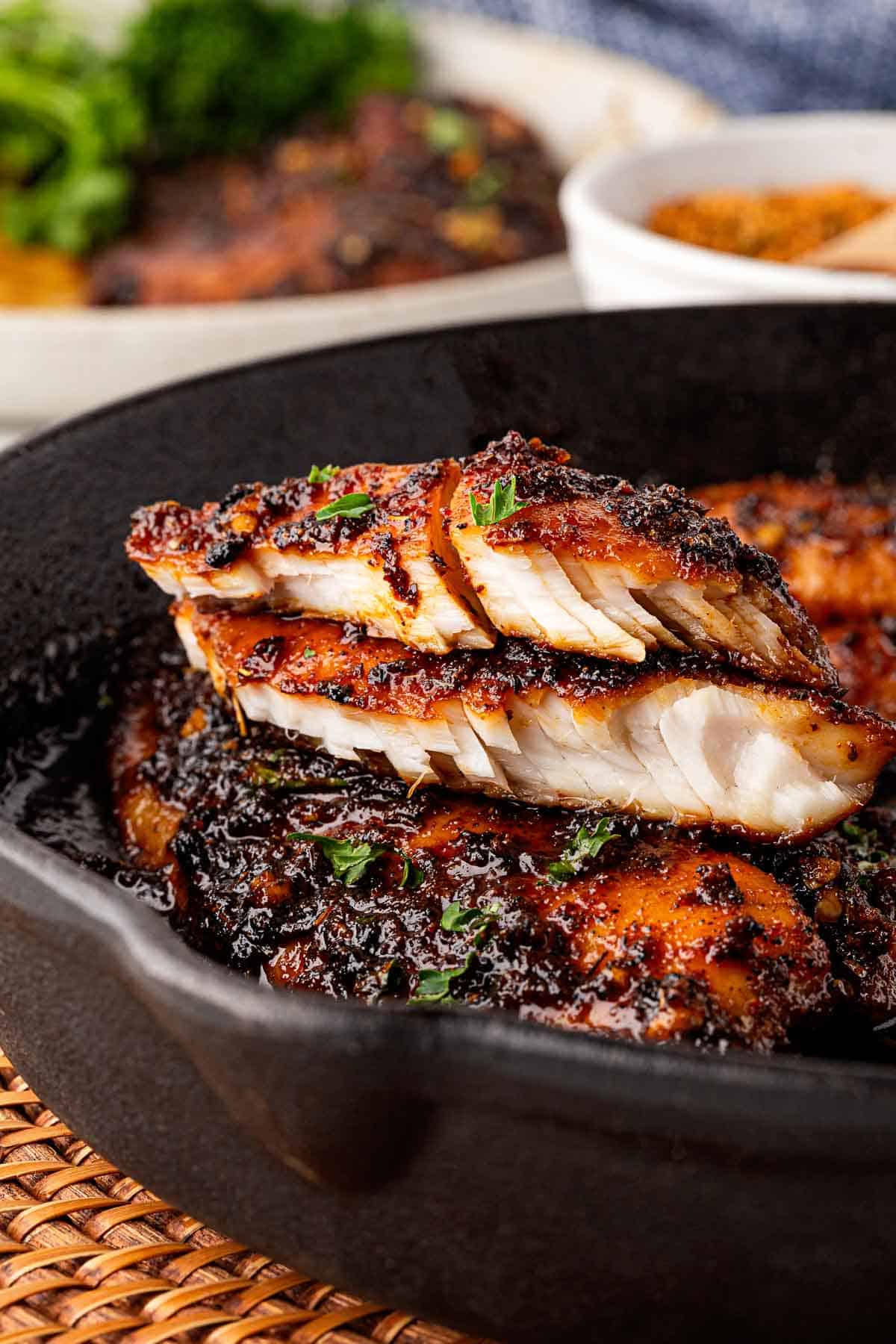 Sliced blackened fish stacked in a skillet showing the flaky interior