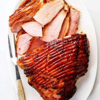 A whole glazed ham with honey with slices of ham ready to serve