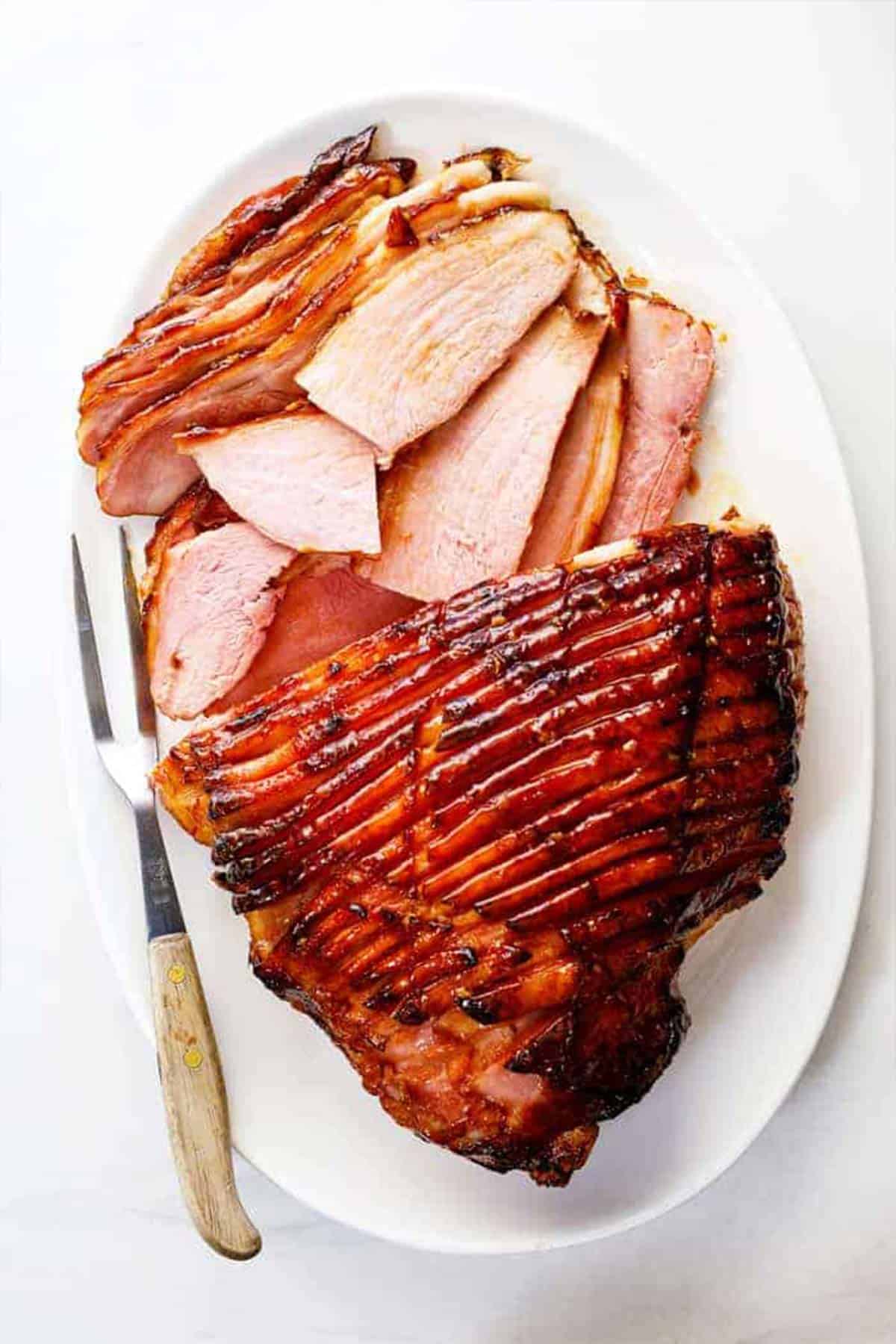 A whole glazed ham with honey with slices of ham ready to serve