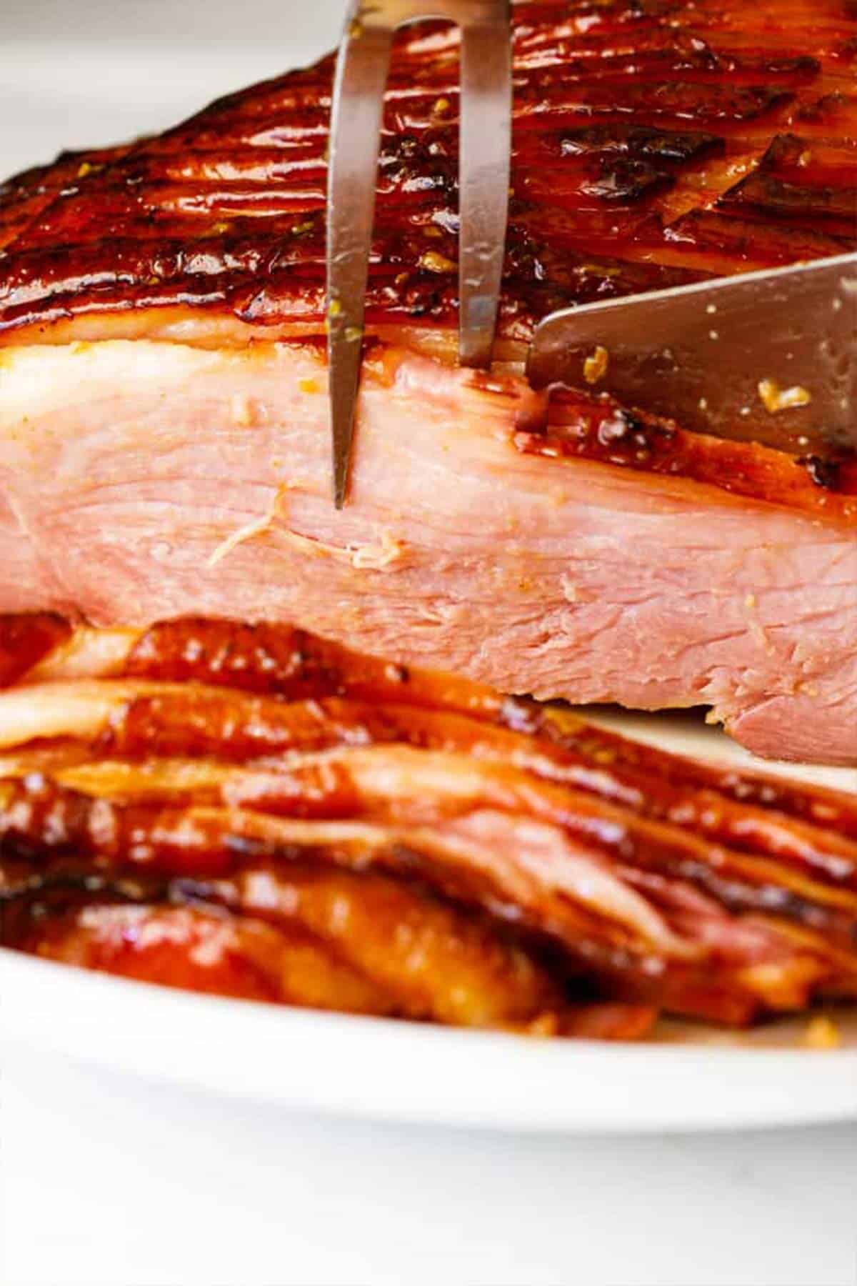 A close up of honey glazed ham being sliced and served