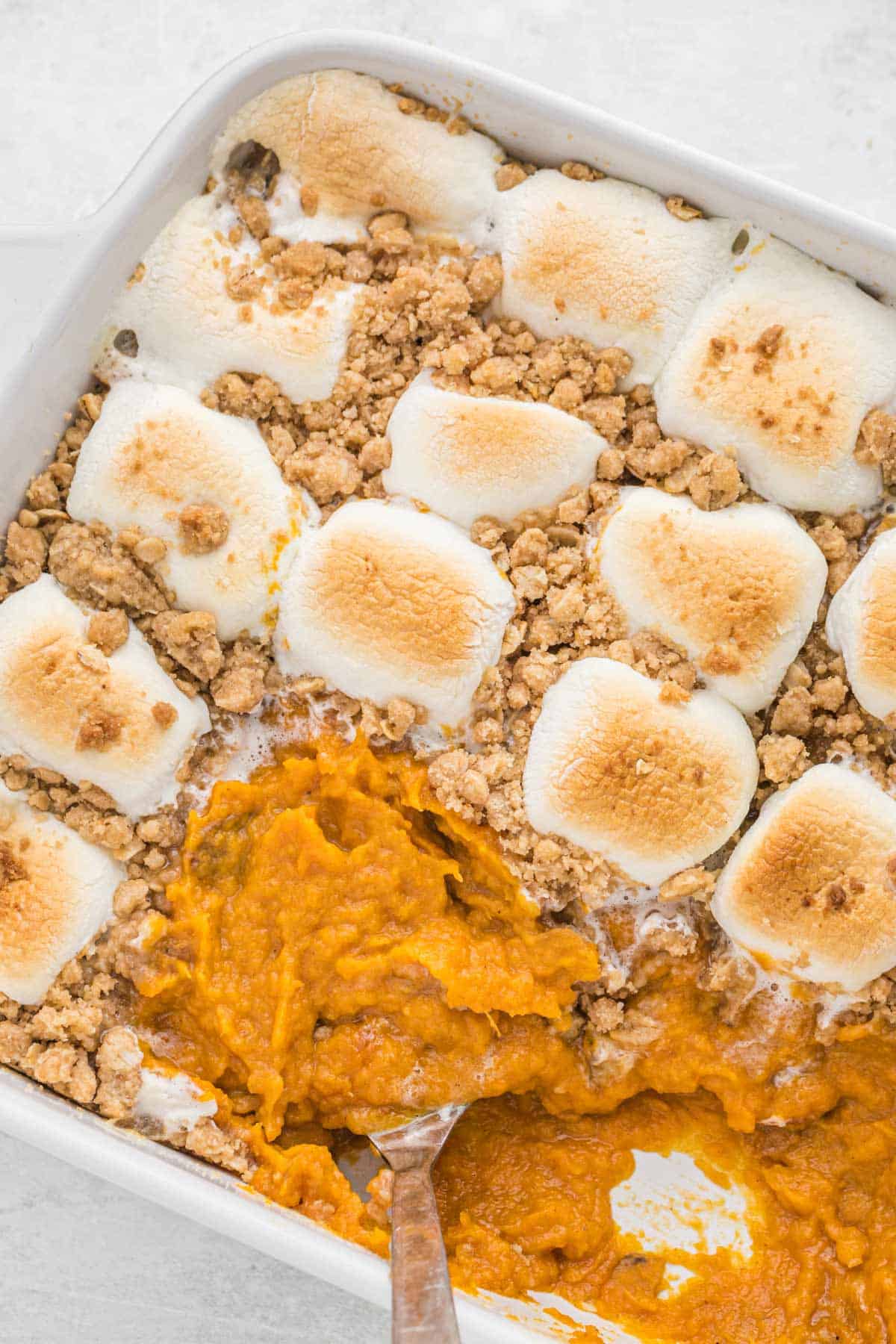 Southern sweet potato casserole recipe on the table with a spoon scooping a serving.
