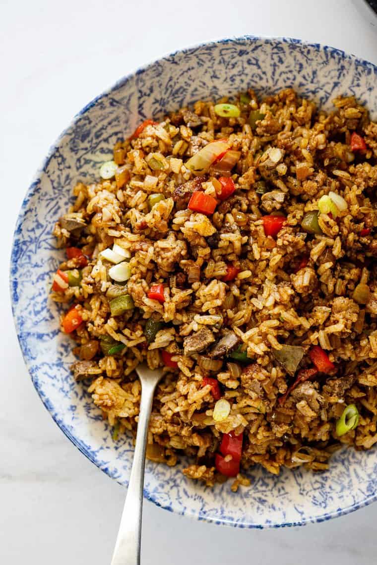 A large plate with dirty rice and a fork ready to serve