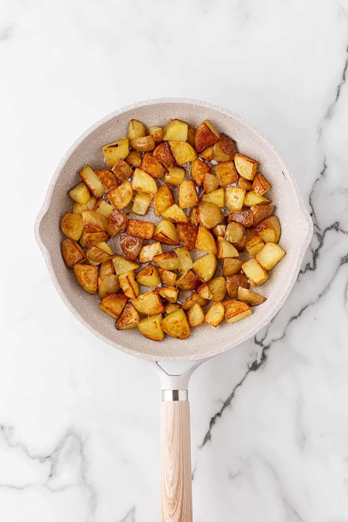Golden brown potatoes cooking in a skillet