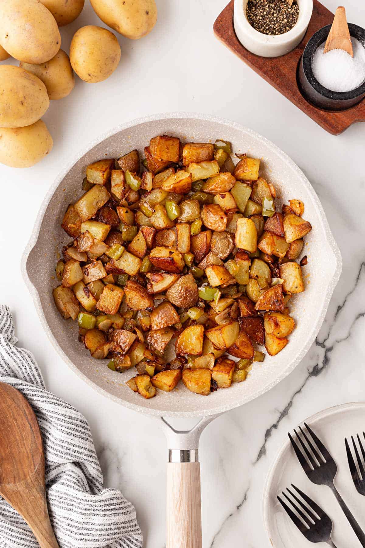 Finished home fries with crispy potatoes, onions, and green peppers in a skillet