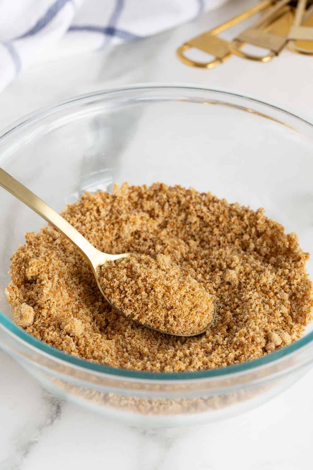 Brown sugar in a glass bowl with a spoon scooping some from the side