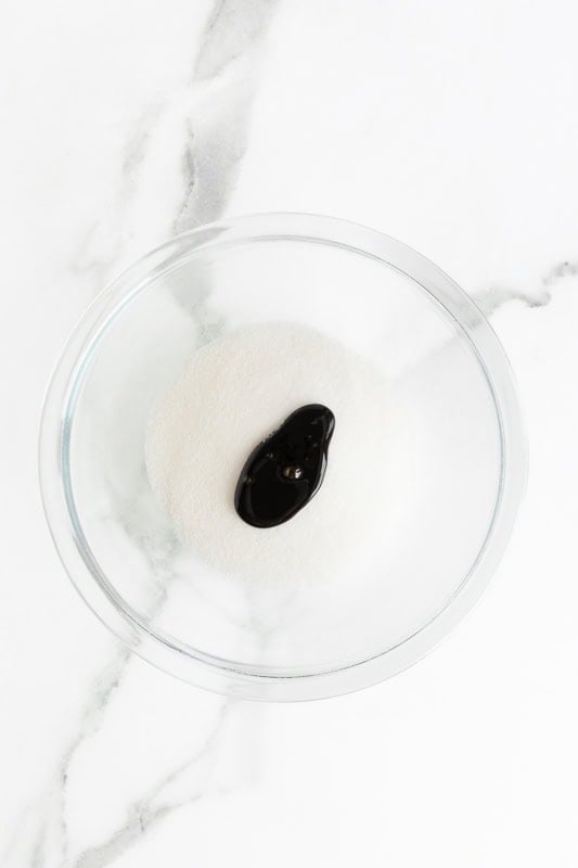 Glass bowl with white sugar and molasses on a marble countertop