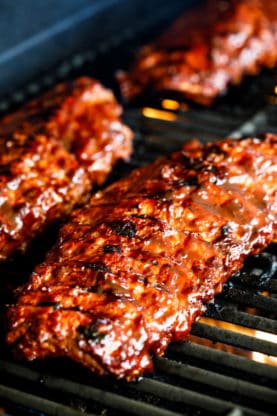 Three racks of baby back ribs being grilled