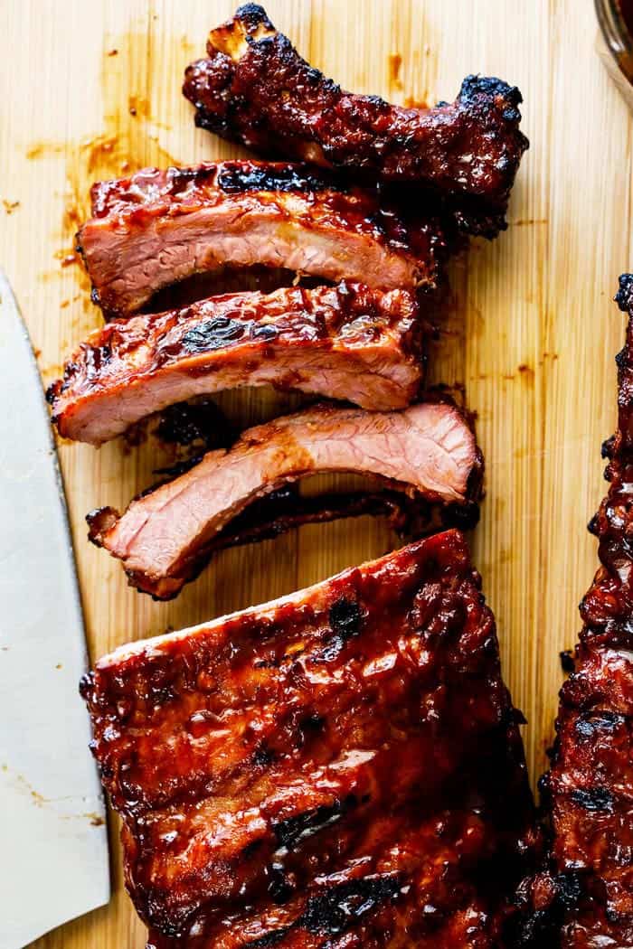 A close up of bbq ribs sliced and ready to serve with barbecue sauce