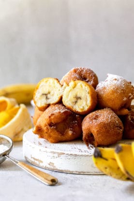 Fritters with banana filling piled high with powdered sugar