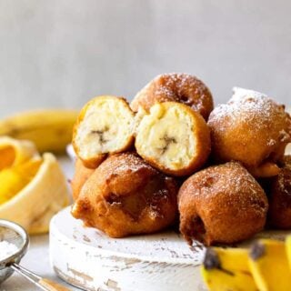 Fritters with banana filling piled high with powdered sugar