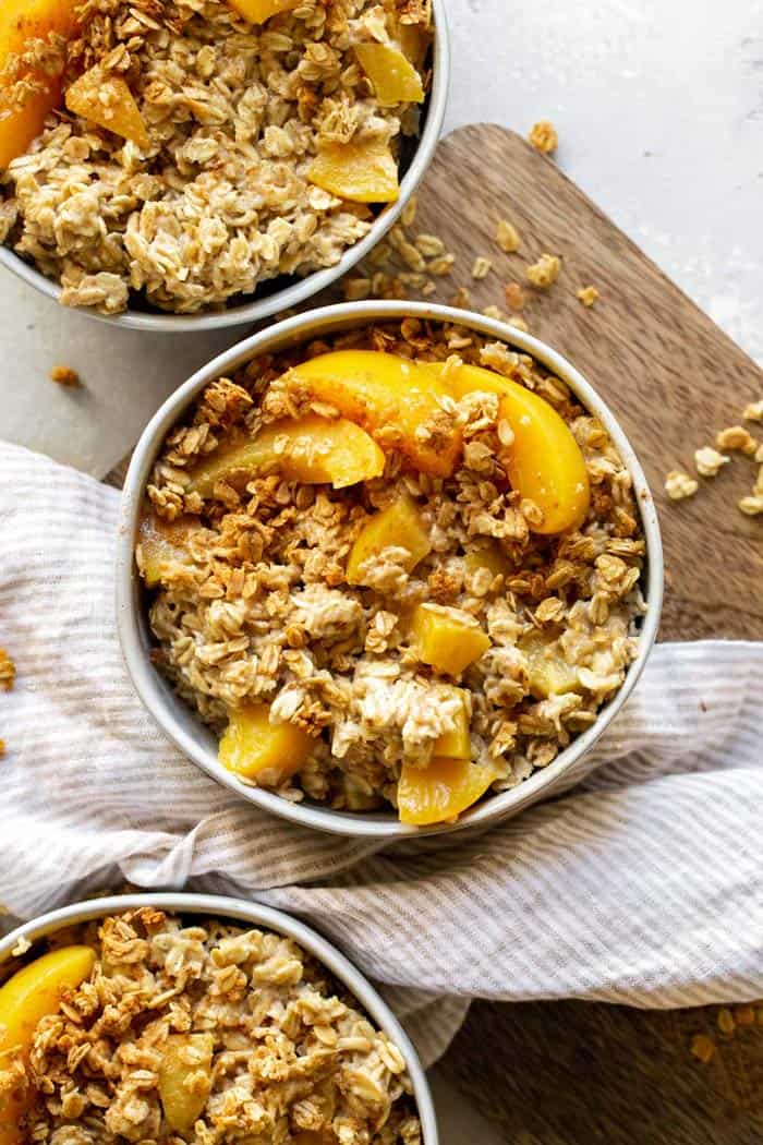 Delicious bowls of peach oatmeal with rolled oats and fresh peaches on table for breakfast