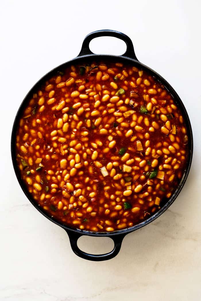 A large cast iron skillet of bbq baked beans ready to serve