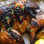 a delicious charred grilled spatchcock chicken sprinkled with herbs next to grilled citrus fruit