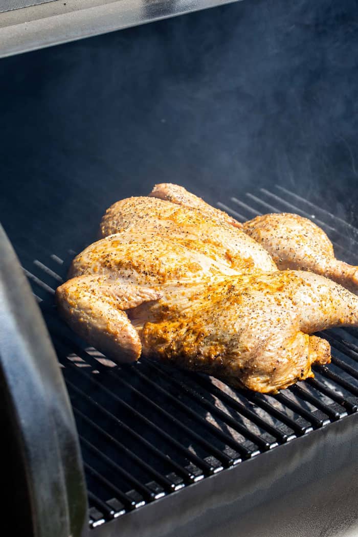 A chicken spiced and seasoned on a grill
