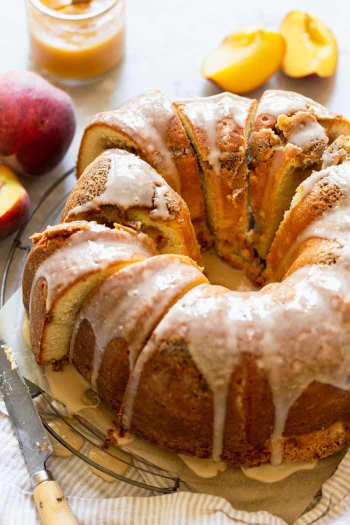 Peach pound cake slices ready to serve with a peach jam filling and fresh peaches nearby