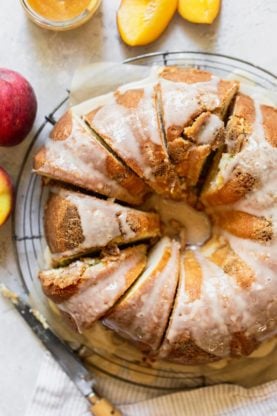 An overhead shot of peach pound cake sliced with fresh peaches nearby