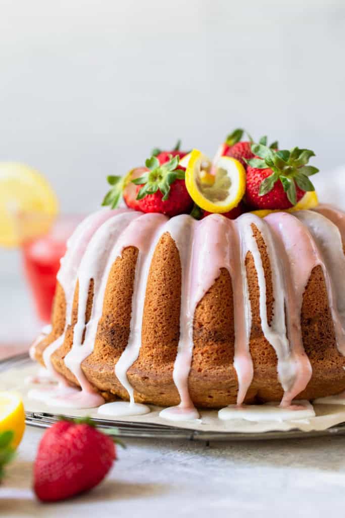 A delicious strawberry lemon flavored bundt cake with citrus glaze and strawberry lemon slice garnishes
