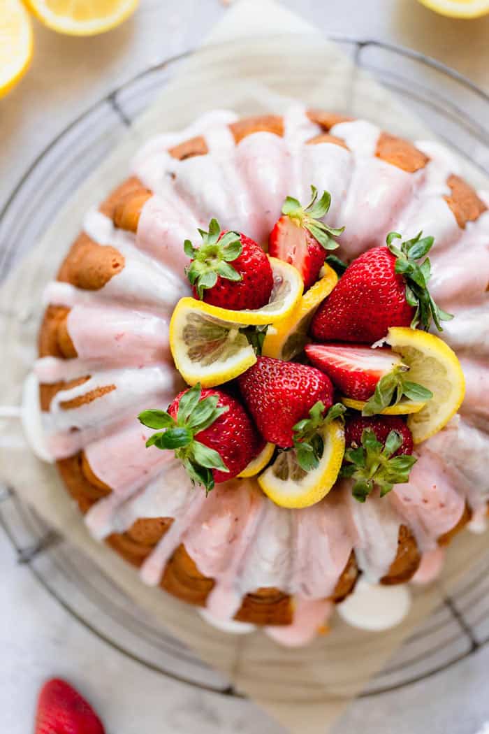 An overhead of a strawberry lemonade pound cake with luscious strawberries and lemon slices garnishes in the center