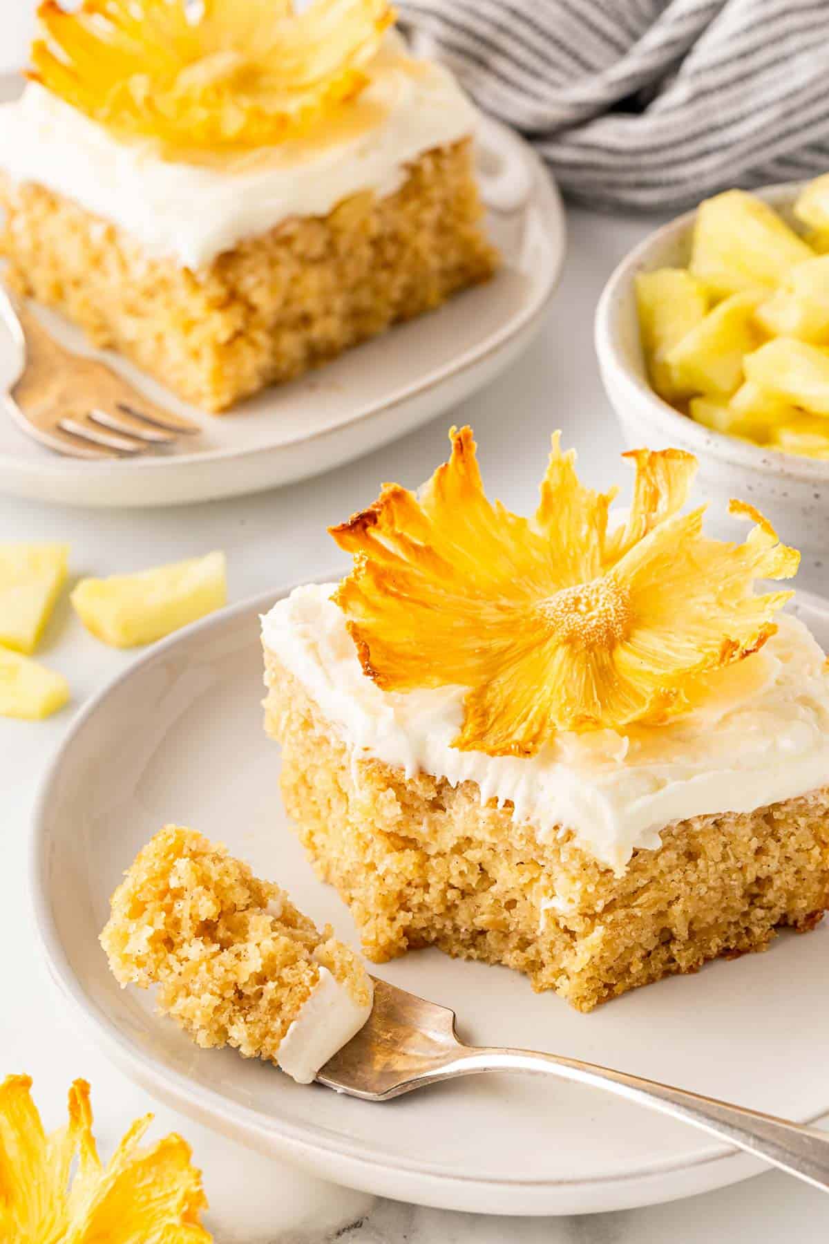 Pineapple cake slice with a bite on a fork and pineapple chunks in the background