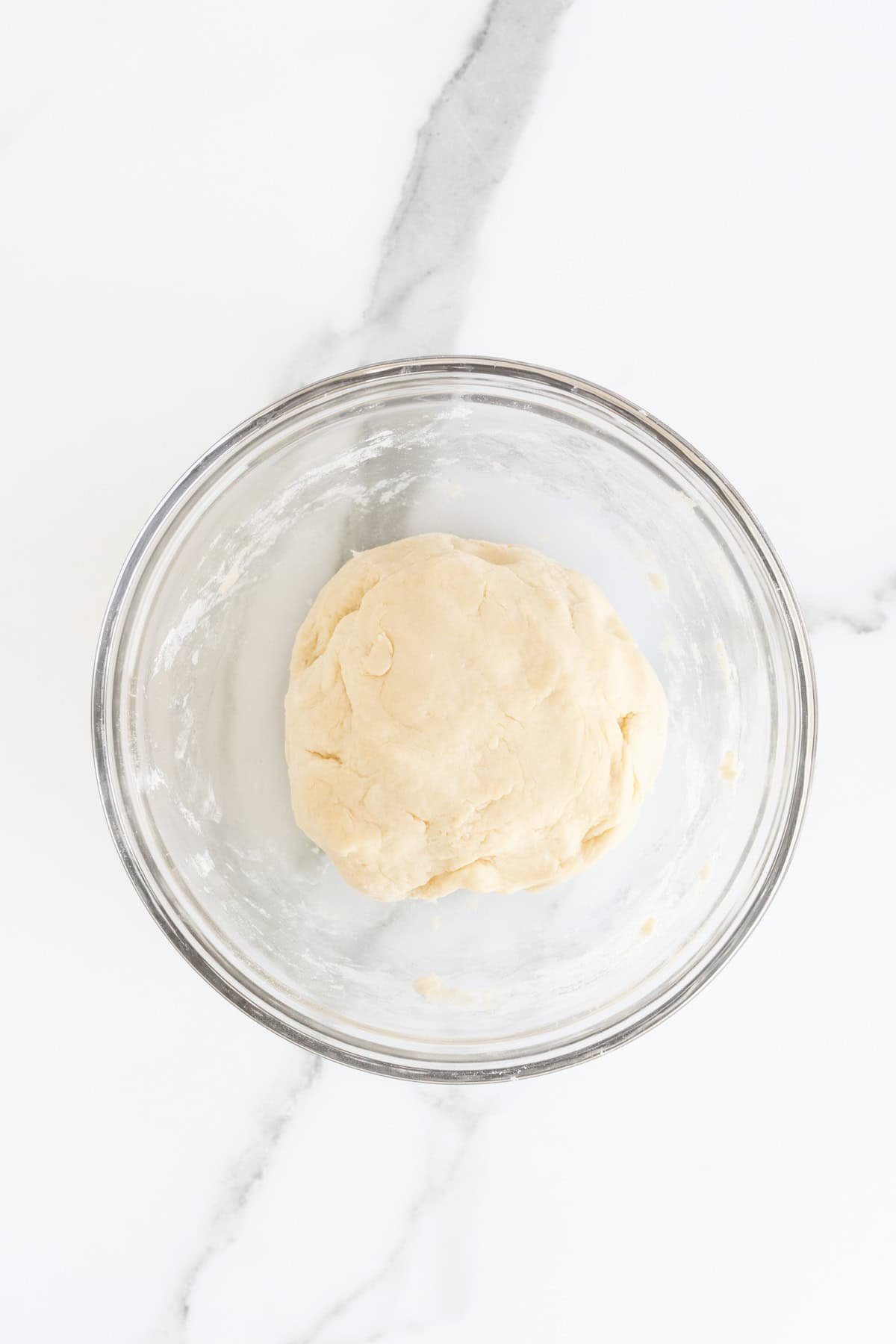 Pie dough formed into a smooth ball in a glass bowl