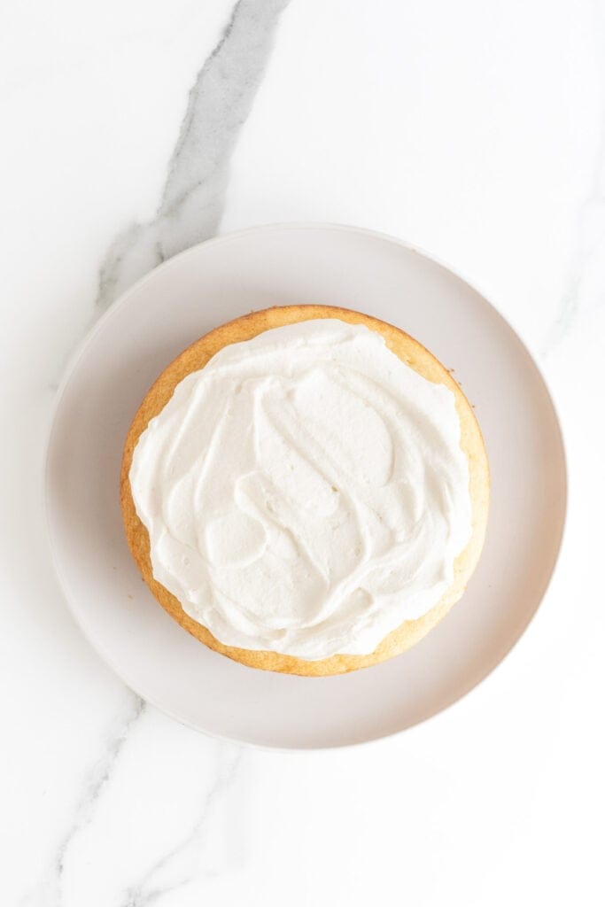 A layer of vanilla shortcake cake with whipped cream spread on top