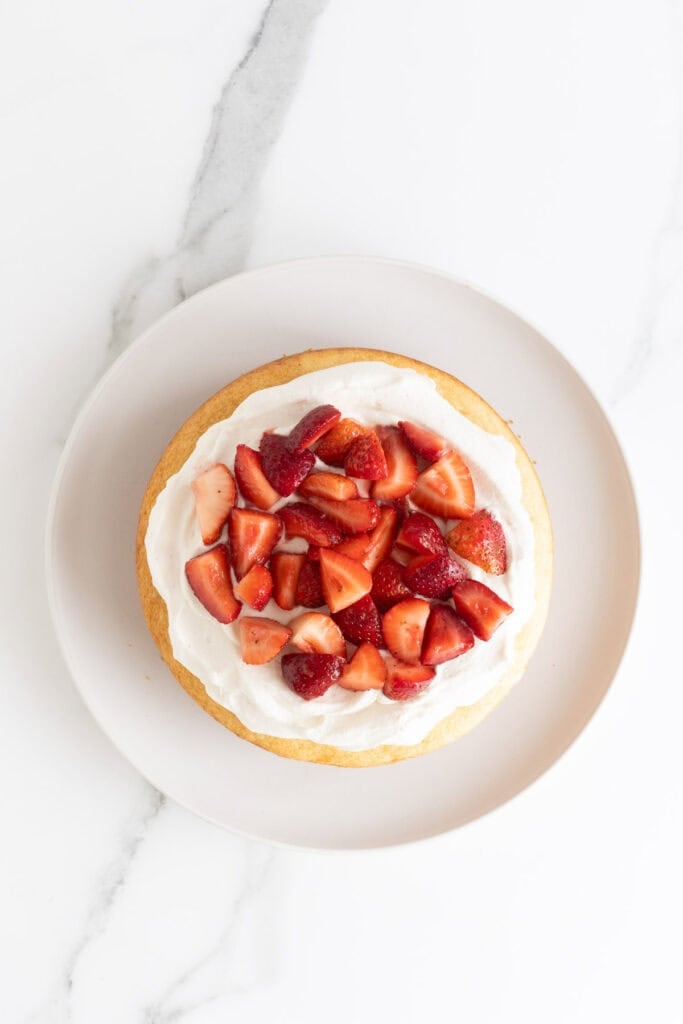 Strawberries added on top of cake layer with whipped cream