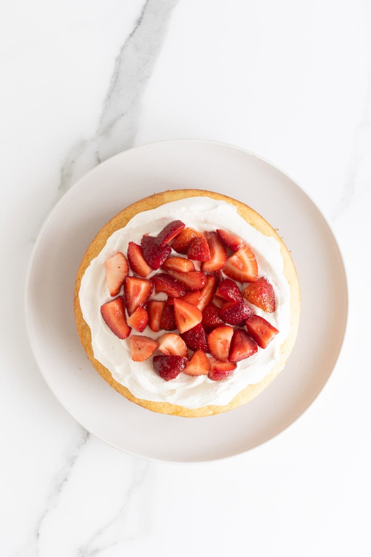 Strawberries added on top of cake layer with whipped cream