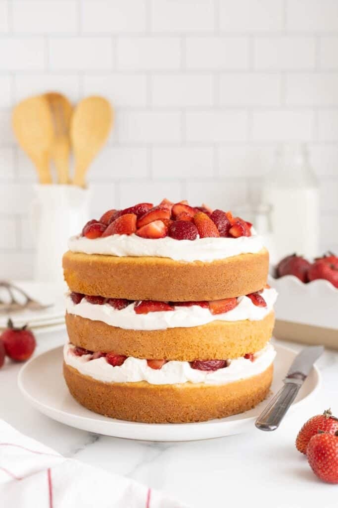 A finished strawberry shortcake cake on a white plate ready to serve