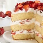 A sliced open strawberry shortcake cake on a white plate