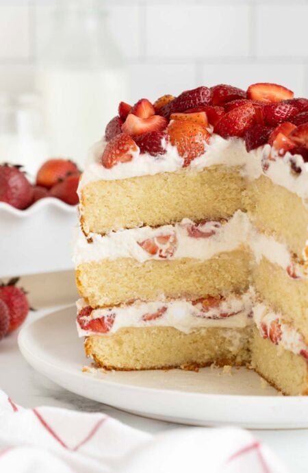 A sliced open strawberry shortcake cake on a white plate