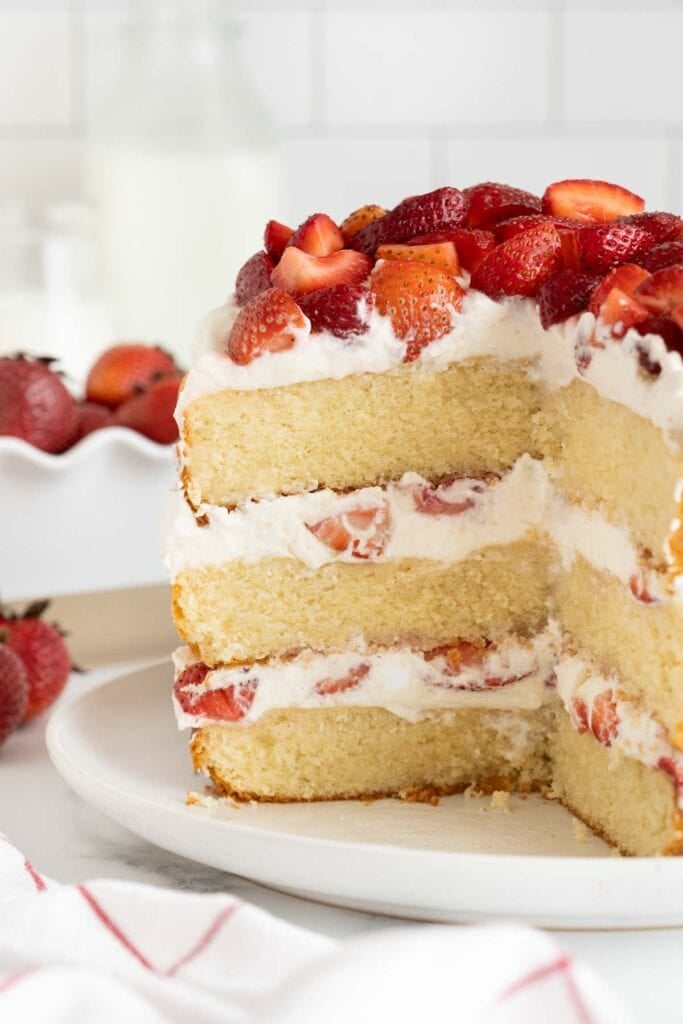 A sliced open strawberry shortcake cake on a white plate