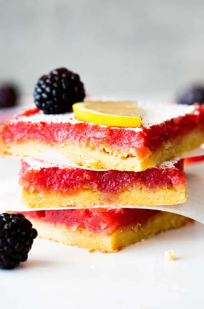 Three blackberry lemon bars stacked with blackberries near