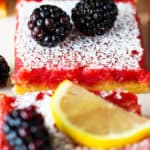 A close up of blackberry bars with lemon filling and confectioner's sugar dusted on top