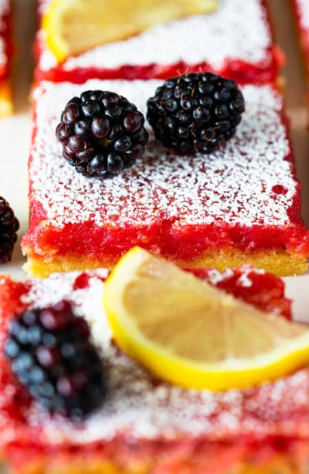 A close up of blackberry bars with lemon filling and confectioner's sugar dusted on top