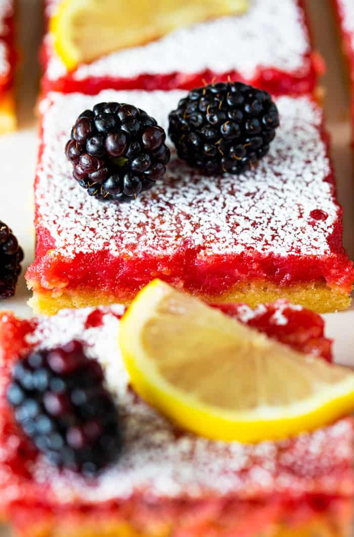 A close up of blackberry bars with lemon filling and confectioner's sugar dusted on top