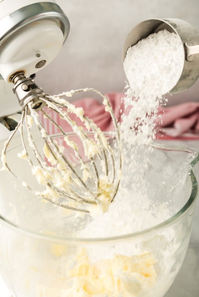 Powdered sugar being added to butter to make caramel buttercream