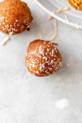 Two pumpkin doughnut holes with confectioner's sugar powdered on top