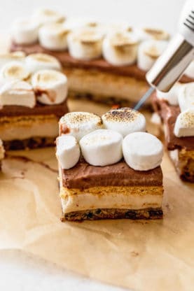 A cookie bar topped with marshmallows being torched