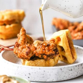 Maple syrup being poured fried chicken and waffles ready to serve for breakfast