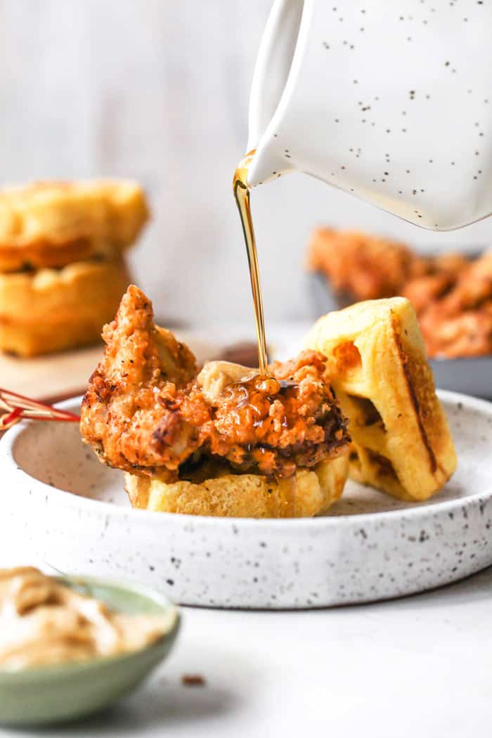Maple syrup being poured fried chicken and waffles ready to serve for breakfast