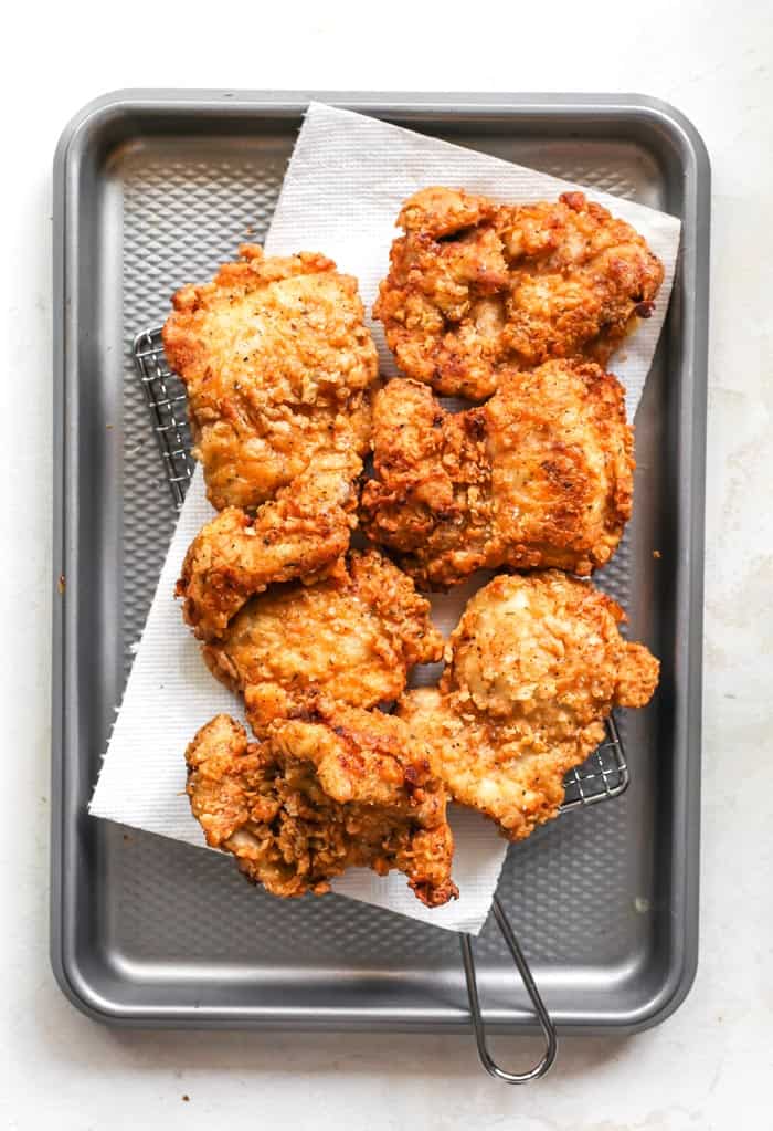 Spicy fried chicken being drained on paper towels