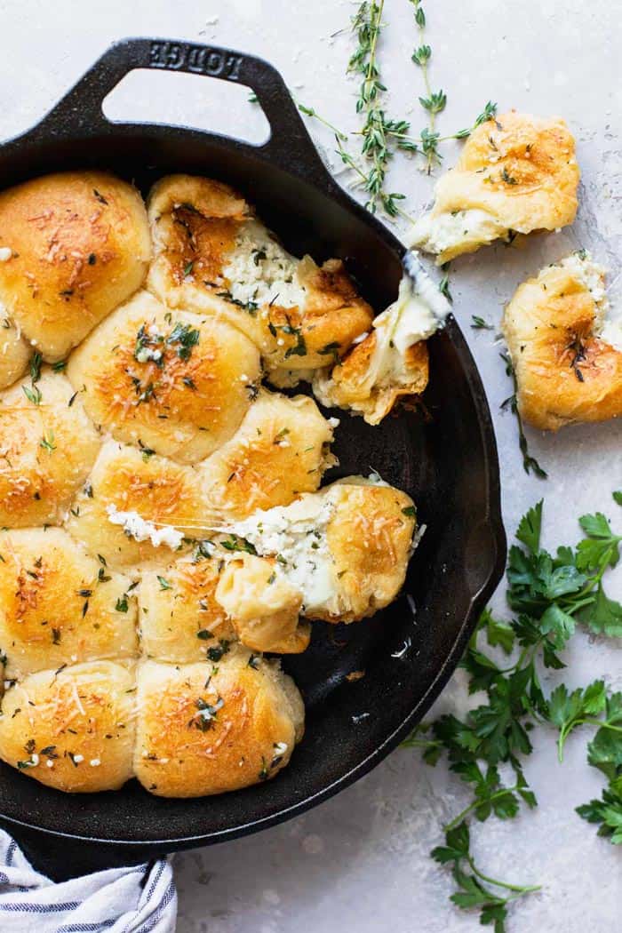 A close up of a cast iron skillet with a couple of rolls with cheese inside