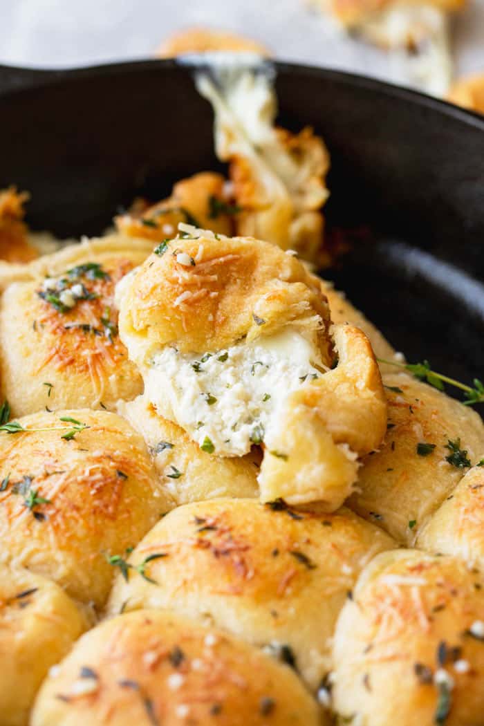 A cast iron skillet with a roll with cheese filled