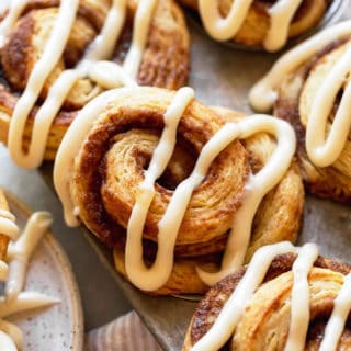 A close up of cinnamon biscuits in tin with a design of icin